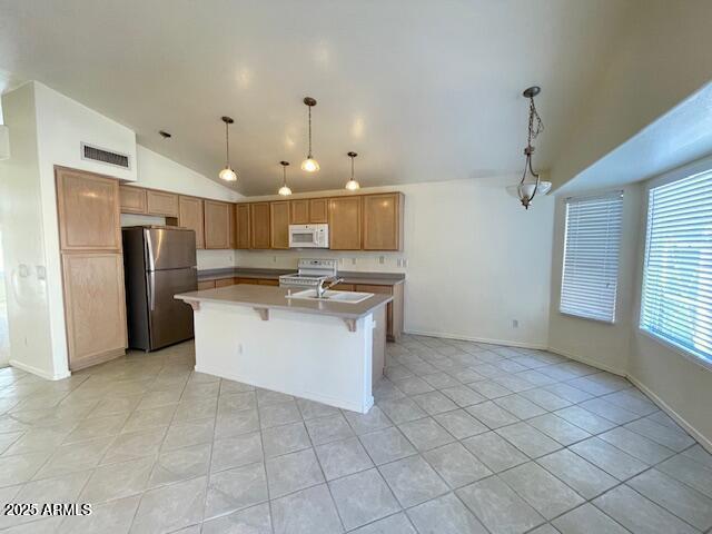 kitchen featuring a kitchen bar, sink, vaulted ceiling, a center island with sink, and white appliances