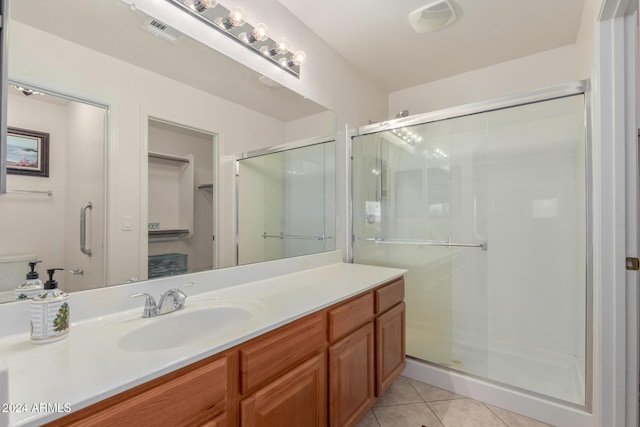 bathroom featuring tile patterned flooring, vanity, and a shower with door