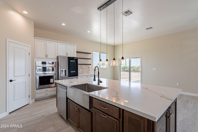 kitchen with white cabinets, decorative light fixtures, stainless steel appliances, and light wood-type flooring