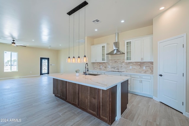 kitchen featuring black electric stovetop, white cabinetry, and a center island with sink