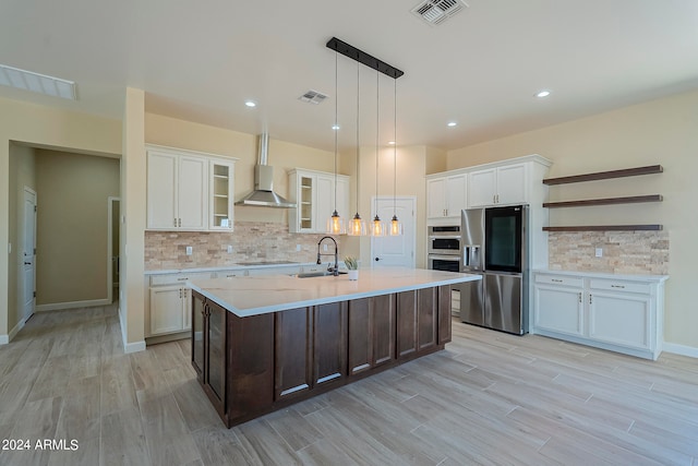 kitchen featuring appliances with stainless steel finishes, wall chimney range hood, and white cabinets