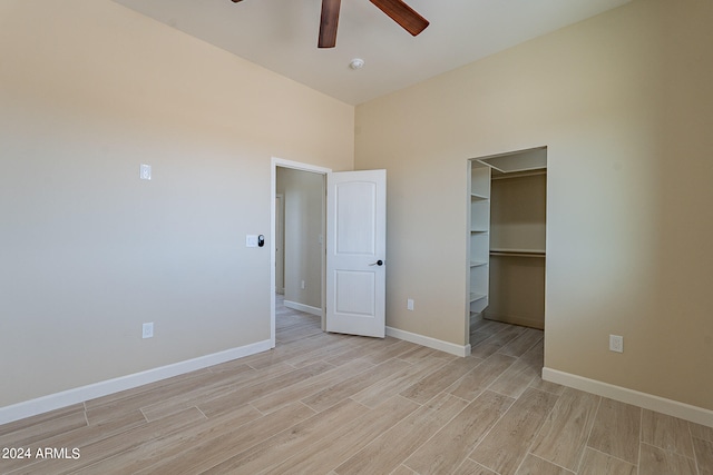 unfurnished bedroom with a spacious closet, a closet, light hardwood / wood-style floors, and ceiling fan