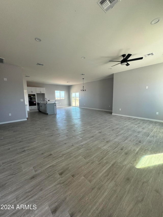 unfurnished living room featuring ceiling fan, wood-type flooring, and sink