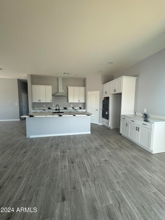 kitchen with double oven, wall chimney exhaust hood, light hardwood / wood-style flooring, sink, and white cabinetry