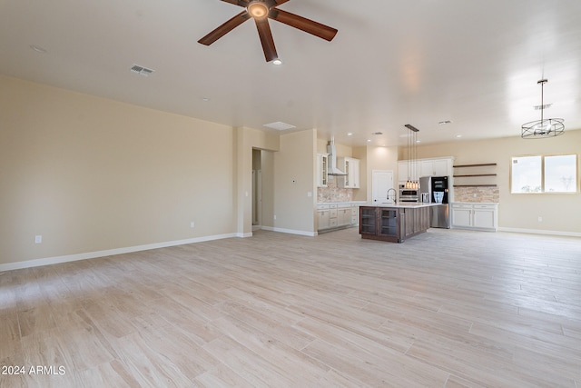 unfurnished living room featuring light hardwood / wood-style floors, sink, and ceiling fan with notable chandelier