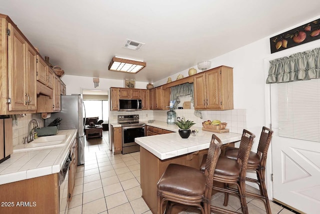 2619 W Lamar Rd, Phoenix, AZ 85017 - kitchen with a sink, appliances with stainless steel finishes, a peninsula, light tile patterned flooring, and decorative backsplash