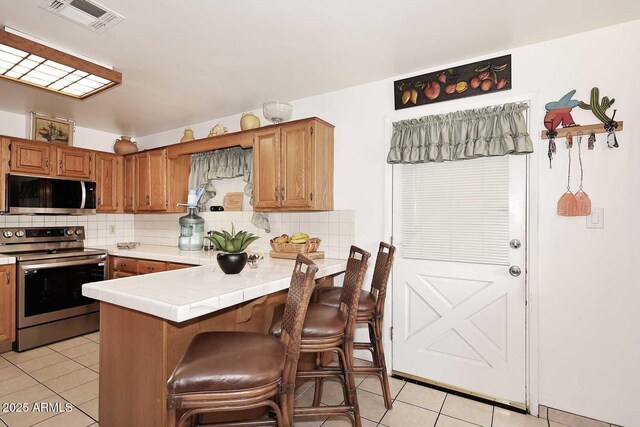 2619 W Lamar Rd, Phoenix, AZ 85017 - kitchen with light tile patterned floors, stainless steel appliances, tasteful backsplash, and visible vents