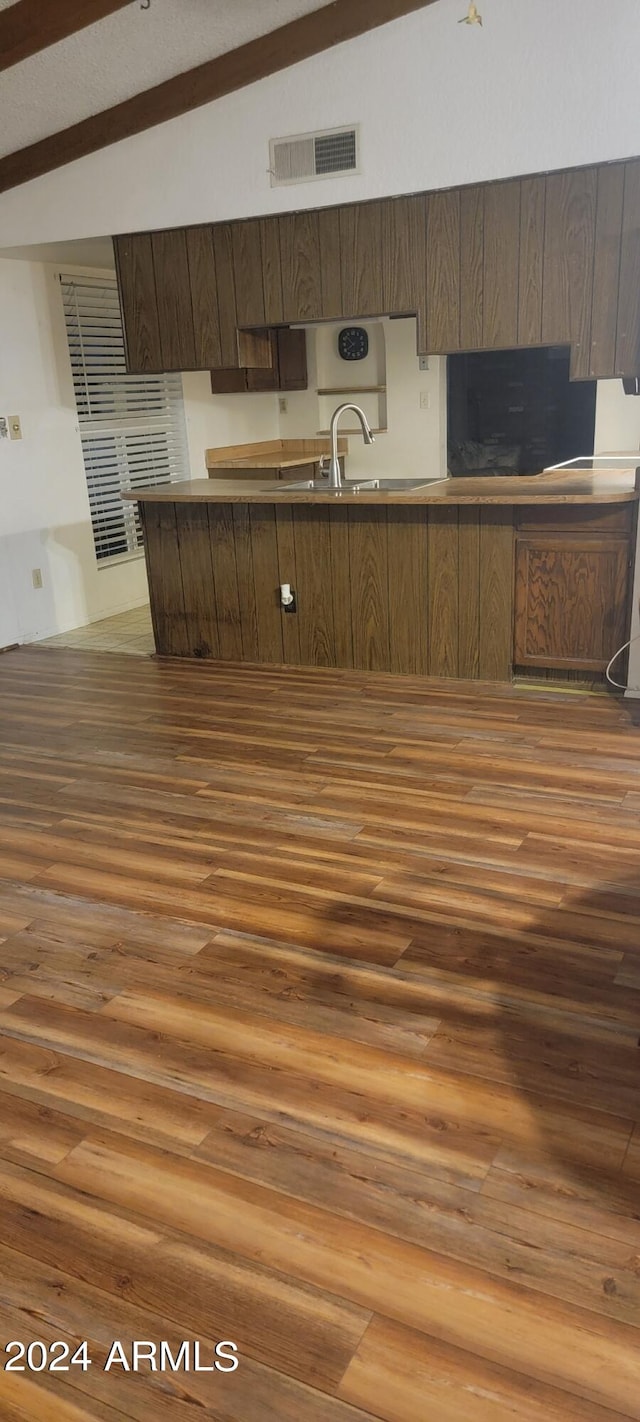 kitchen with sink, beamed ceiling, and dark wood-type flooring