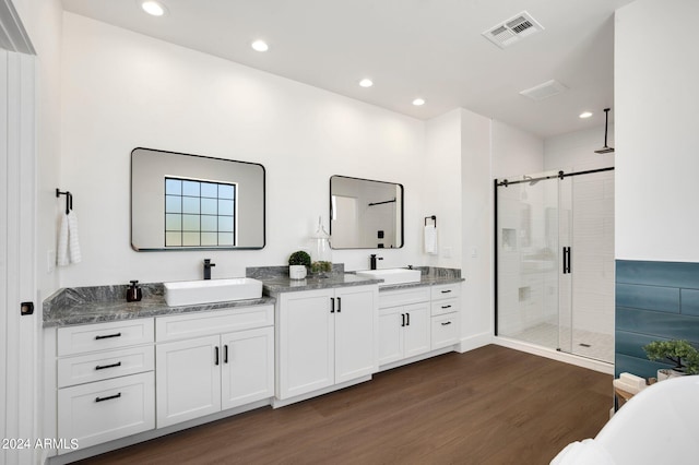 bathroom featuring hardwood / wood-style floors, double sink vanity, and an enclosed shower