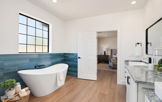 bathroom featuring hardwood / wood-style floors, tile walls, a bath, and large vanity