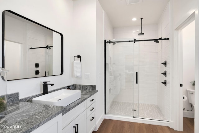 bathroom featuring a shower with door, vanity, hardwood / wood-style flooring, and toilet