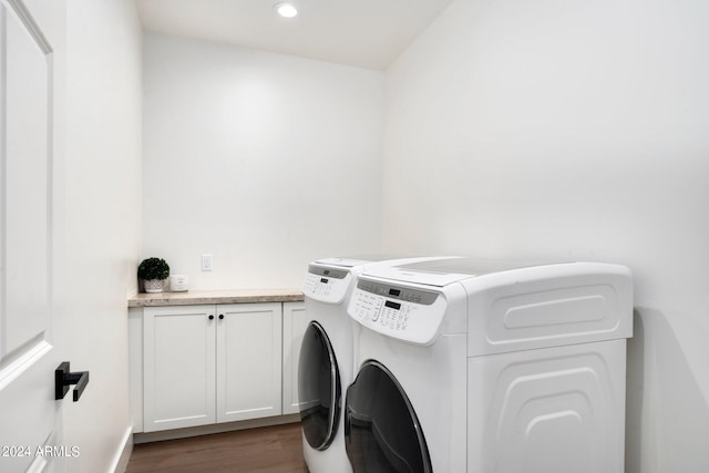 laundry room featuring cabinets, dark hardwood / wood-style floors, and washer and clothes dryer