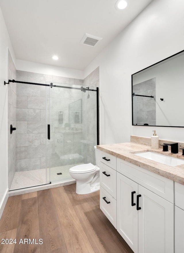 bathroom with an enclosed shower, vanity, hardwood / wood-style flooring, and toilet