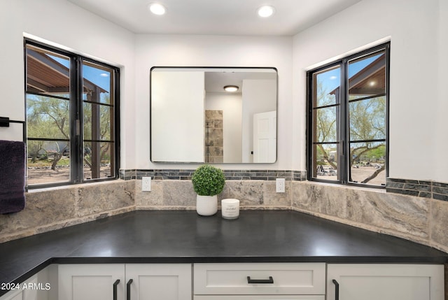 kitchen featuring a wealth of natural light, tasteful backsplash, and white cabinets