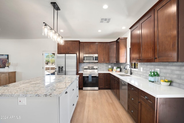 kitchen with backsplash, stainless steel appliances, light hardwood / wood-style floors, sink, and a center island