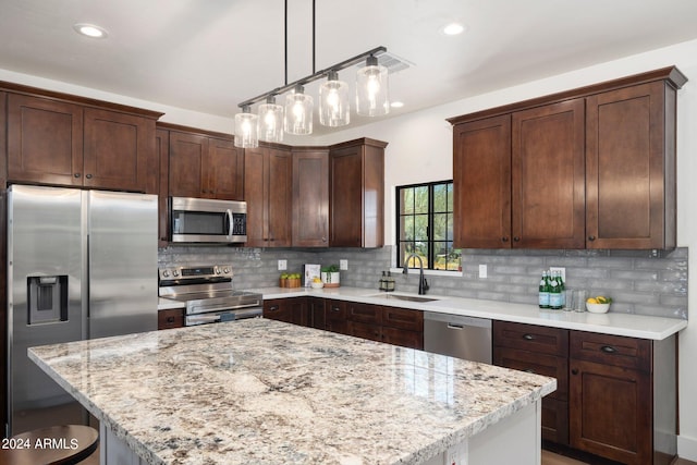 kitchen with pendant lighting, stainless steel appliances, dark brown cabinets, sink, and tasteful backsplash