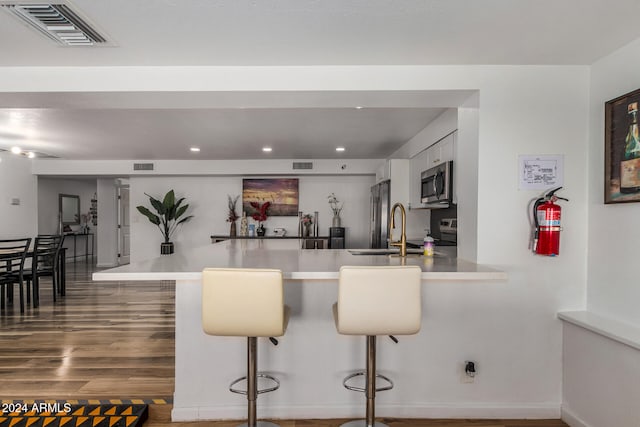 kitchen featuring a kitchen bar, kitchen peninsula, white cabinets, and sink