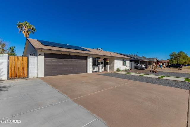 ranch-style home featuring a garage and solar panels