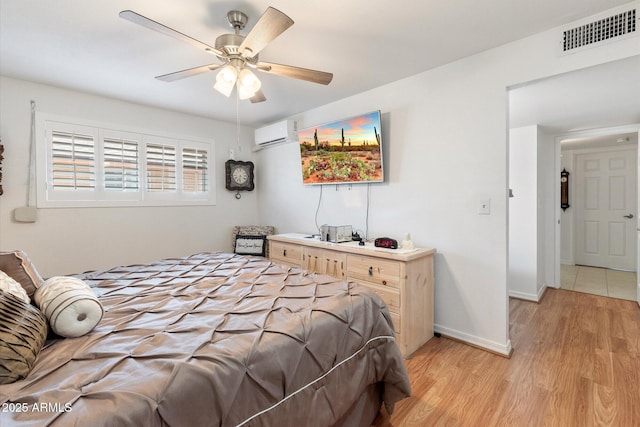 bedroom with ceiling fan, a wall mounted AC, and light wood-type flooring