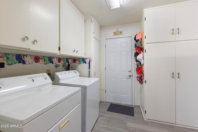 laundry area with cabinets, light hardwood / wood-style floors, and washer and dryer