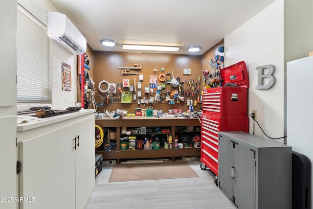 miscellaneous room with a wall mounted air conditioner, light hardwood / wood-style flooring, and a workshop area