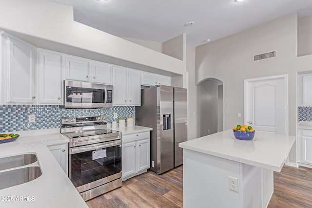 44853 W Jack Rabbit Trl, Maricopa, AZ 85139 - kitchen featuring appliances with stainless steel finishes, arched walkways, white cabinets, decorative backsplash, and light countertops