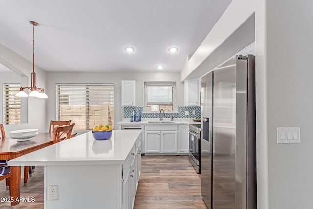 44853 W Jack Rabbit Trl, Maricopa, AZ 85139 - kitchen with appliances with stainless steel finishes, light countertops, white cabinets, tasteful backsplash, and wood finished floors