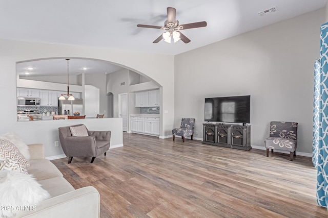 44853 W Jack Rabbit Trl, Maricopa, AZ 85139 - living room featuring arched walkways, a ceiling fan, wood finished floors, and vaulted ceiling