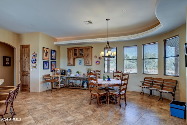 dining area with an inviting chandelier, a tray ceiling, and light tile patterned floors