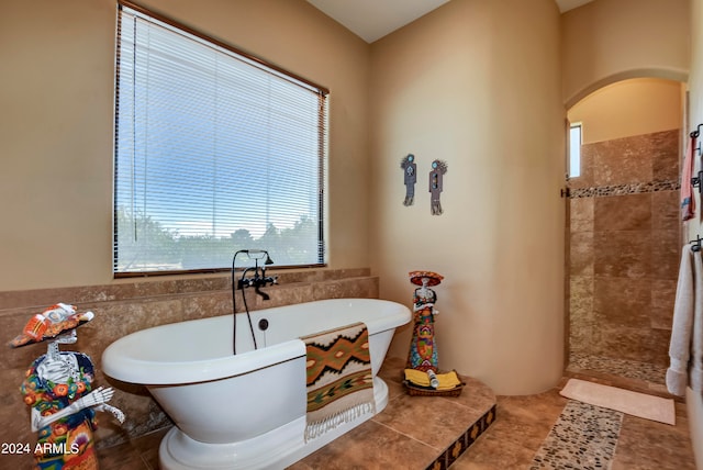 bathroom with a bathing tub, tile patterned flooring, and a healthy amount of sunlight