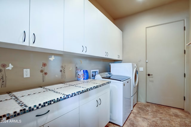 washroom featuring light tile patterned flooring, washing machine and clothes dryer, and cabinets