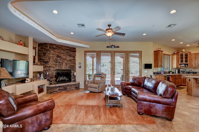 tiled living room with a stone fireplace, french doors, and ceiling fan