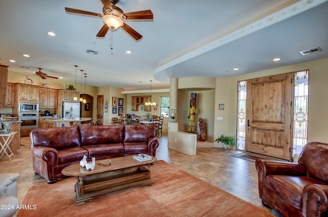 living room featuring ceiling fan with notable chandelier and light tile patterned floors