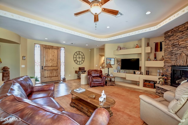 living room with light tile patterned floors, a stone fireplace, and ceiling fan