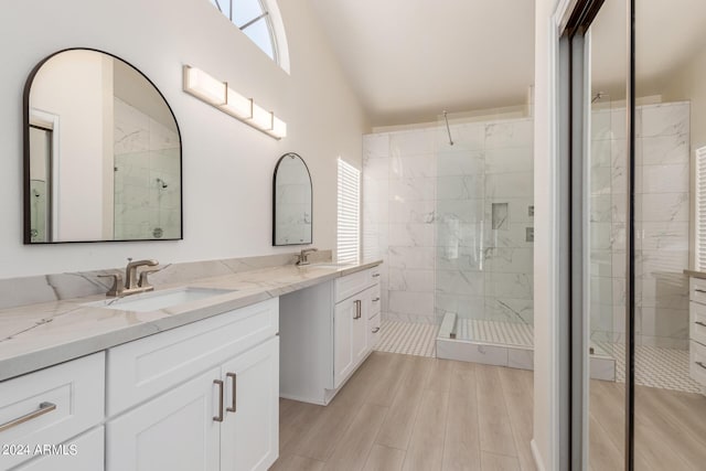 bathroom featuring hardwood / wood-style floors, vanity, a tile shower, and lofted ceiling