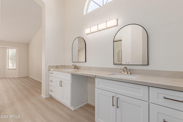 bathroom featuring vanity, wood-type flooring, and lofted ceiling