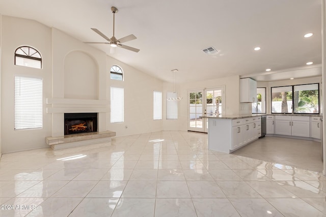 kitchen with a tile fireplace, white cabinetry, ceiling fan, stainless steel dishwasher, and kitchen peninsula