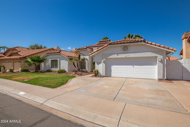 mediterranean / spanish-style home featuring a front lawn and a garage