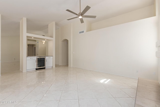 unfurnished room featuring ceiling fan, a high ceiling, and beverage cooler