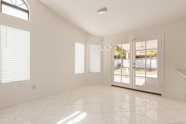 unfurnished dining area with french doors, light tile patterned flooring, and vaulted ceiling