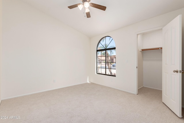 unfurnished bedroom with a walk in closet, light carpet, a closet, and ceiling fan