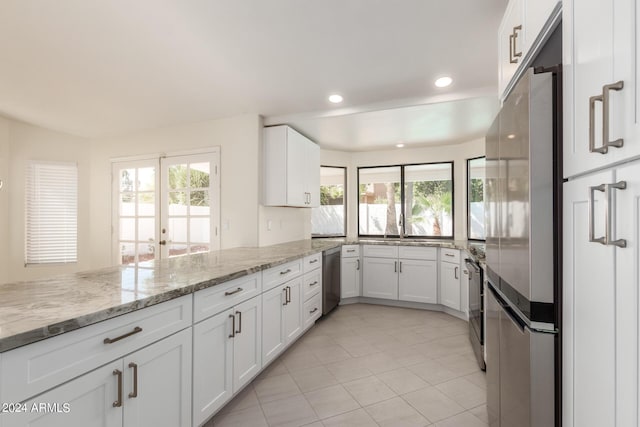 kitchen featuring french doors, white cabinets, light tile patterned floors, light stone countertops, and appliances with stainless steel finishes