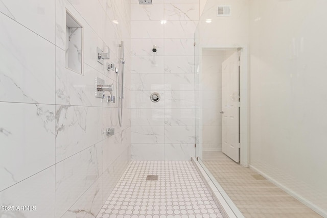 bathroom with a tile shower and tile patterned floors