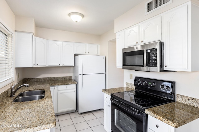 kitchen with sink, white cabinetry, dark stone countertops, black / electric stove, and white fridge