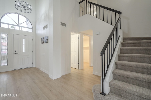 foyer with a high ceiling, a notable chandelier, and light hardwood / wood-style floors