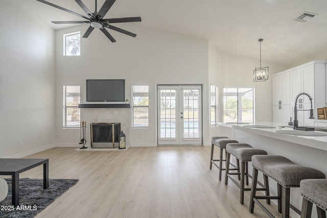 kitchen with sink, a tile fireplace, white cabinets, french doors, and light wood-type flooring