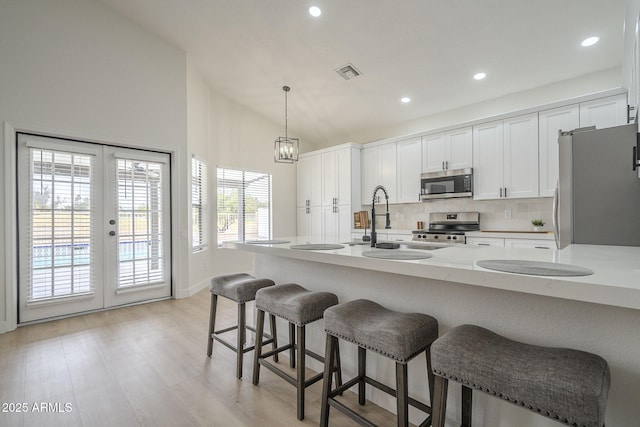 kitchen with pendant lighting, white cabinetry, sink, stainless steel appliances, and french doors