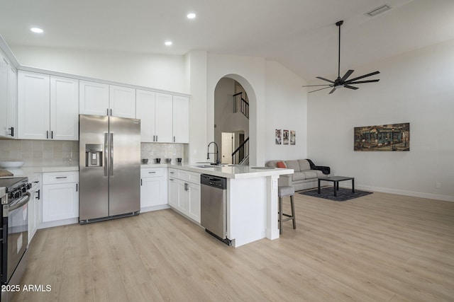 kitchen with sink, appliances with stainless steel finishes, a kitchen breakfast bar, kitchen peninsula, and white cabinets