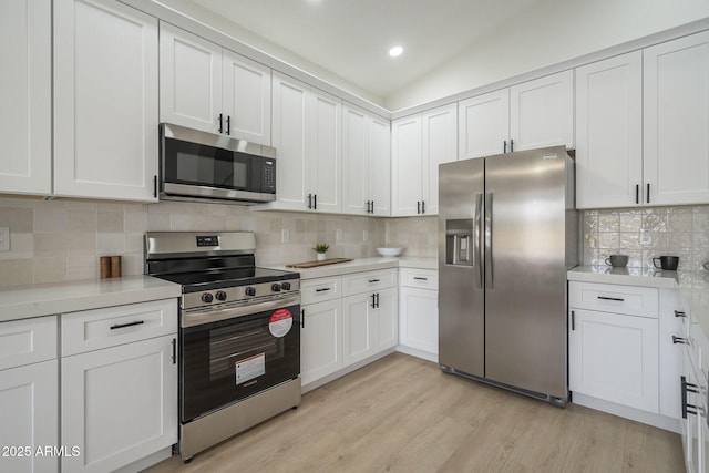 kitchen featuring tasteful backsplash, appliances with stainless steel finishes, light hardwood / wood-style floors, and white cabinets