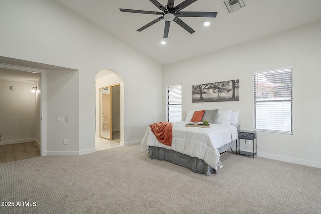 bedroom featuring light carpet, ensuite bath, high vaulted ceiling, and ceiling fan